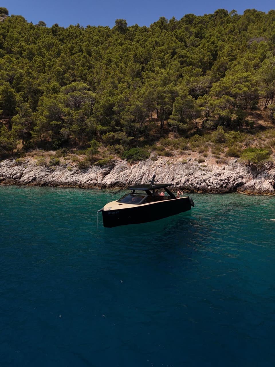 Black-hulled Colnago 35 resting in clear Adriatic water off a rocky shore