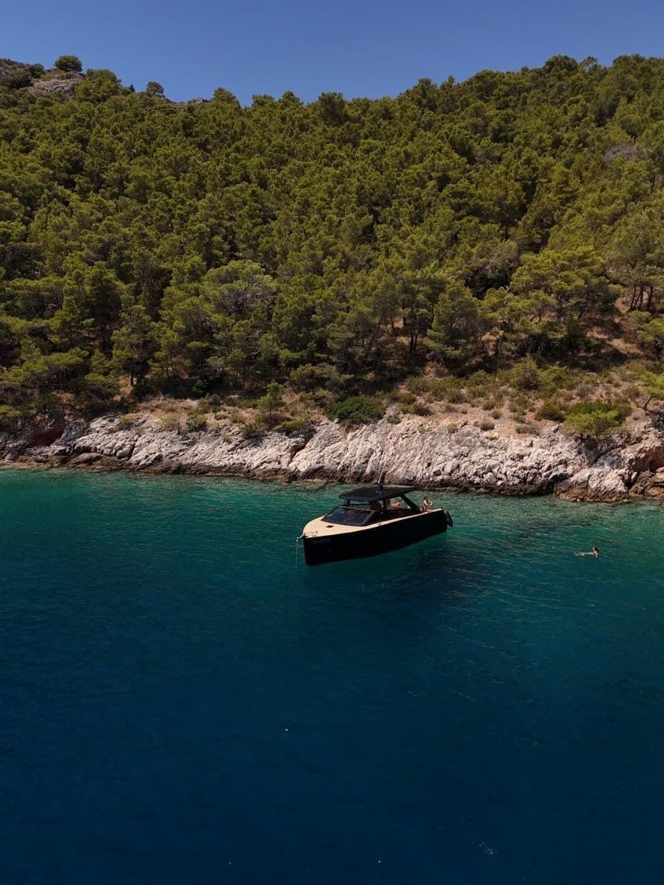 Colnago 35 anchored in emerald water with a guest swimming off the stern